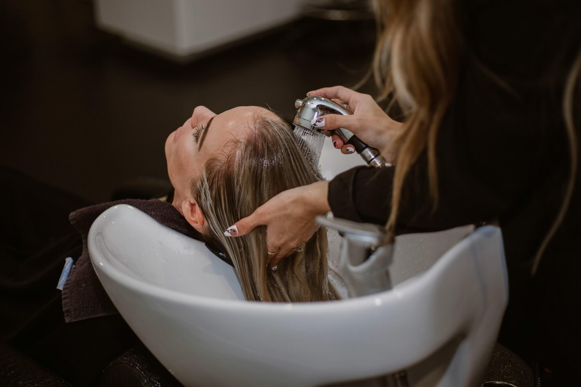 Image of lady washing and running her hands through highlighted hair in basin