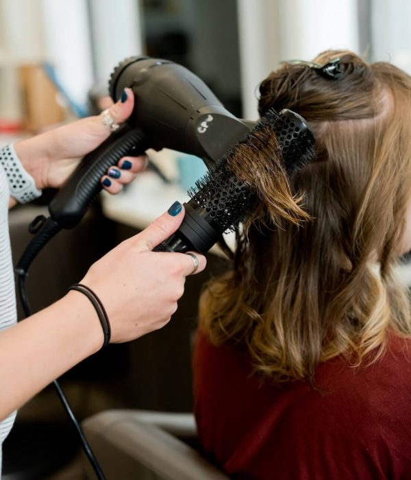 Stylist blow drying and running a hairbrush through a clients hair